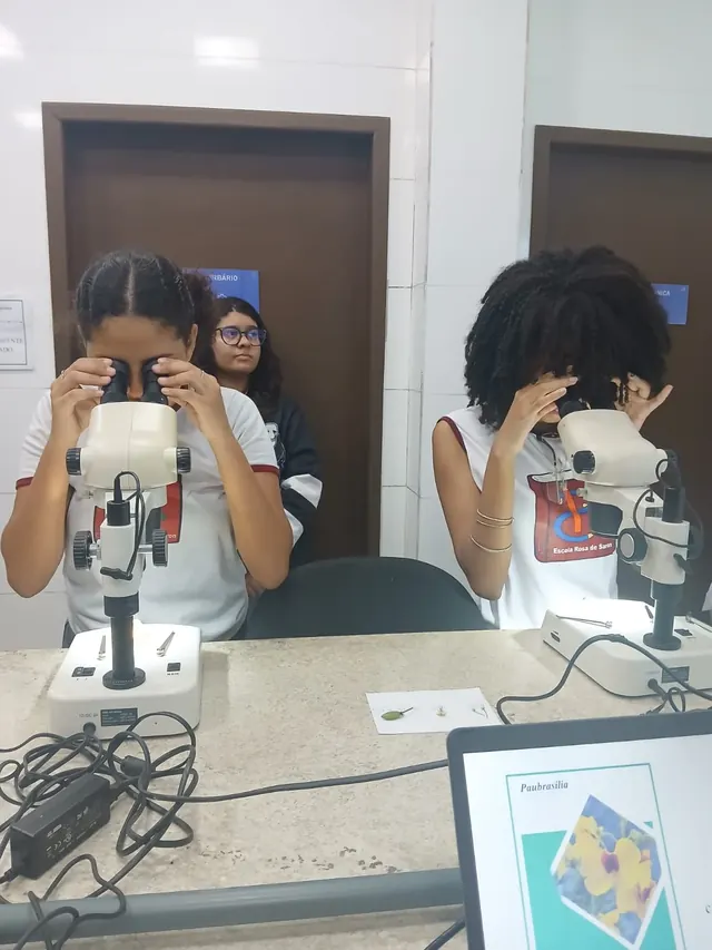 Duas alunas observando amostras em lupas no herbário