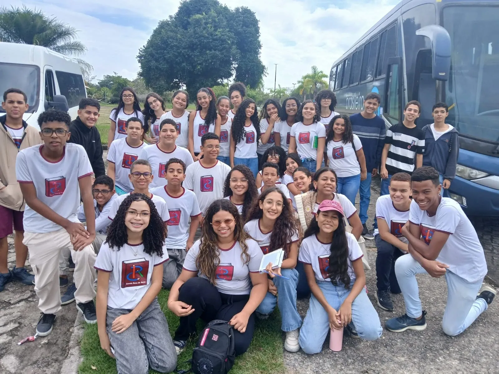 Alunos uniformizados posando em frente aos ônibus do passeio